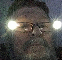man wearing glasses with lights on sides sitting in the dark