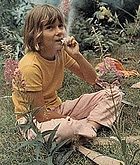 Child in yellow shirt sitting in meadow eating