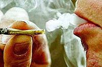 Person smoking hand-rolled cigarette, exhaling smoke