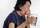 woman choking while taking a drink of water