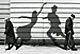 two old people shuffling along while their shadows dance madly on a wall behind them