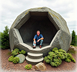 an image of a man sitting in a hollowed out large boulder