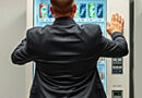 a man is a business suit shaking a vending machine in anger