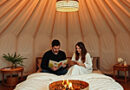 a couple reading in a luxurious bed in a glamping yurt
