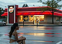 a young woman sitting barefooted in a Wendy's parking lot