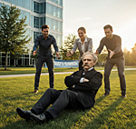 Business team participating in a team building exercise outdoors. His coworkers failed to catch a seated man, Friedrich Nietzsche.