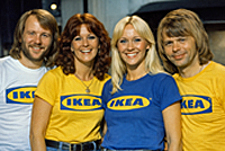 Four ABBA members in 1976 wear bright IKEA T‑shirts under warm stage lights, smiling with cheerful precision that echoes IKEA Desk Assembly Instructions.