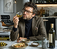 Man in modern kitchen examines olive oil like a sommelier, surrounded by curated tools and ingredients that promise to transform your cooking habits