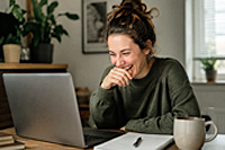 Ordinary woman laughing at a spreadsheet on a laptop, reacting to a weekly performance review with amused disbelief.