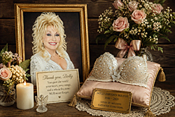 Dolly Parton's breasts are remembered in a sentimental memorial tribute featuring her portrait, flowers, candlelight, rhinestones, and a keepsake.