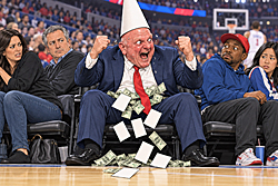 Steve Ballmer, Clippers Owner, wears an enormous dunce cap courtside as money and draft cards tumble around him and uncomfortable spectators recoil.